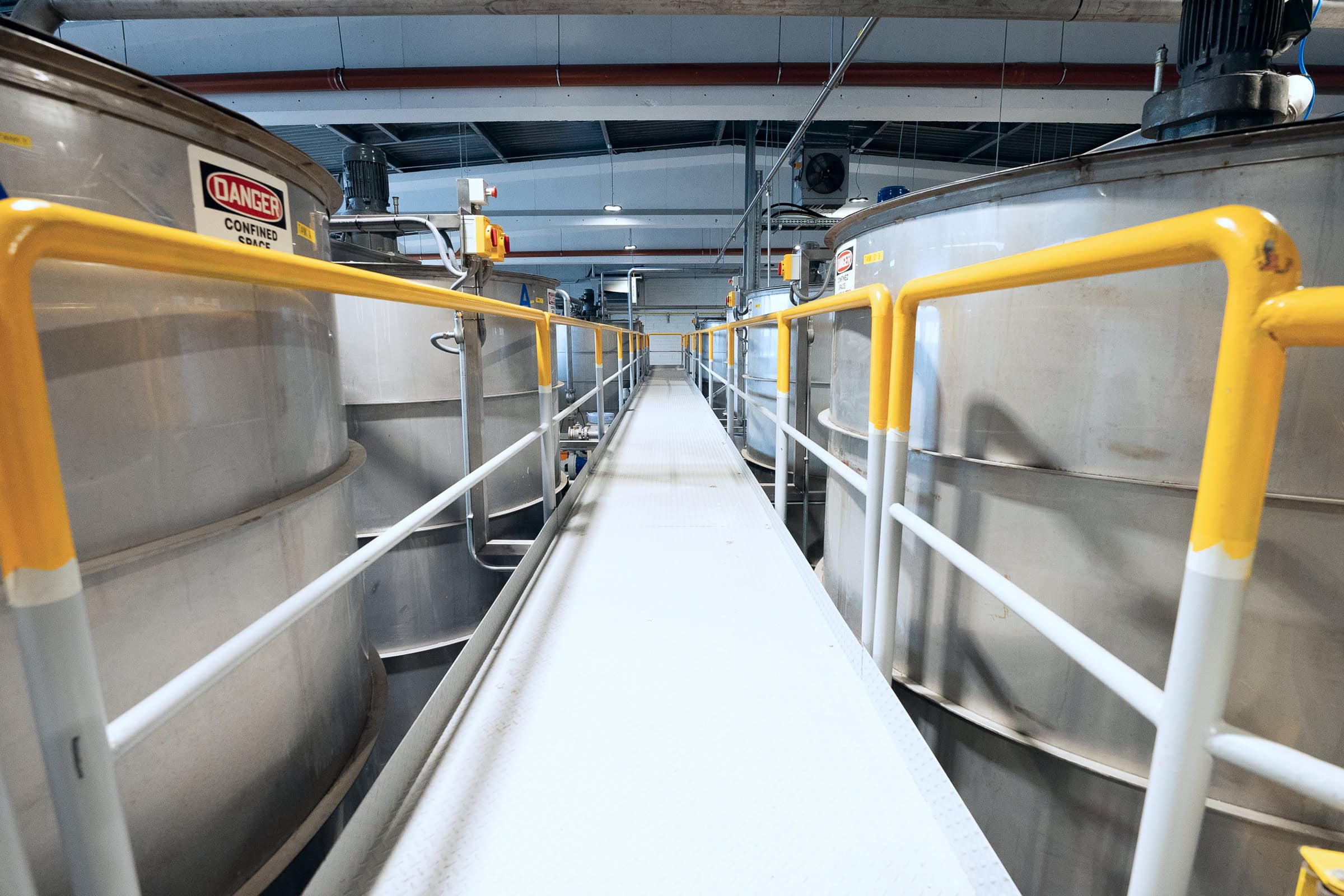 Wide-angle shot looking down an elevated walkway, with large vats on either side